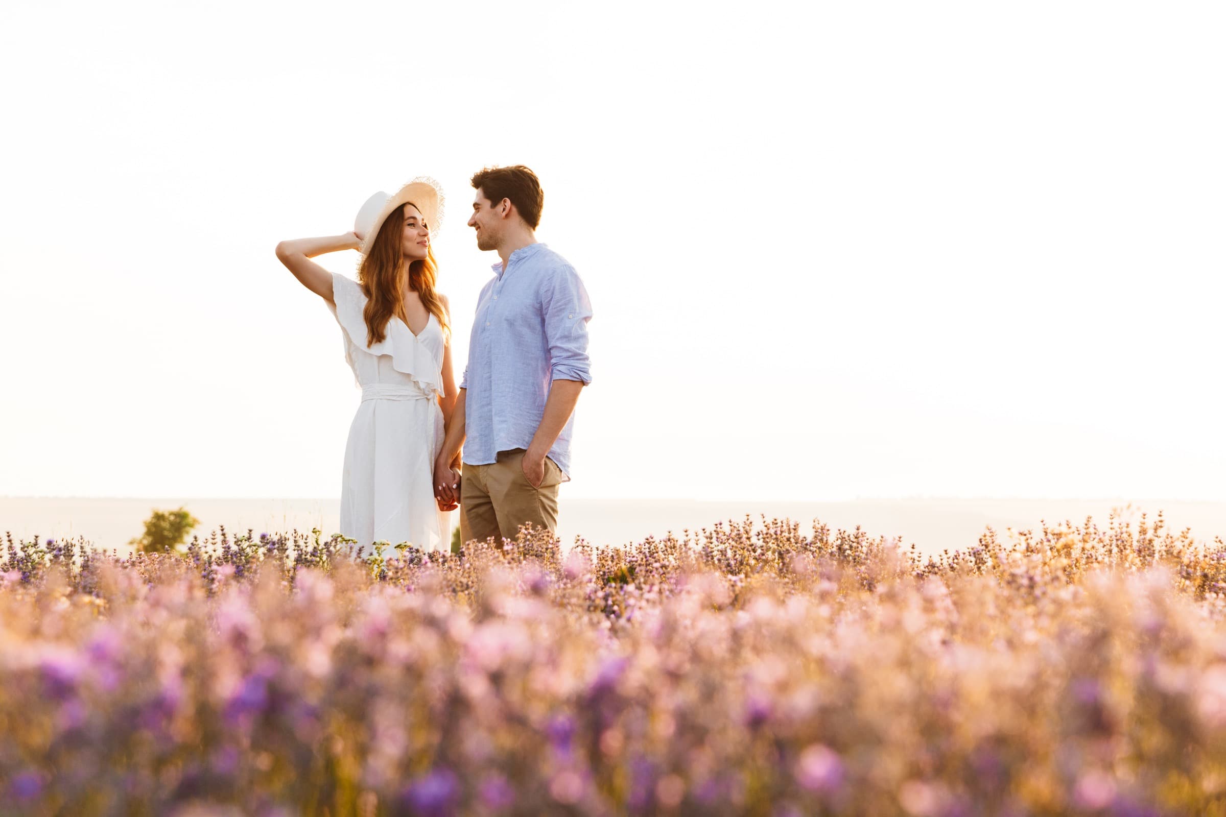 Couple standing together in a flower field at golden hour