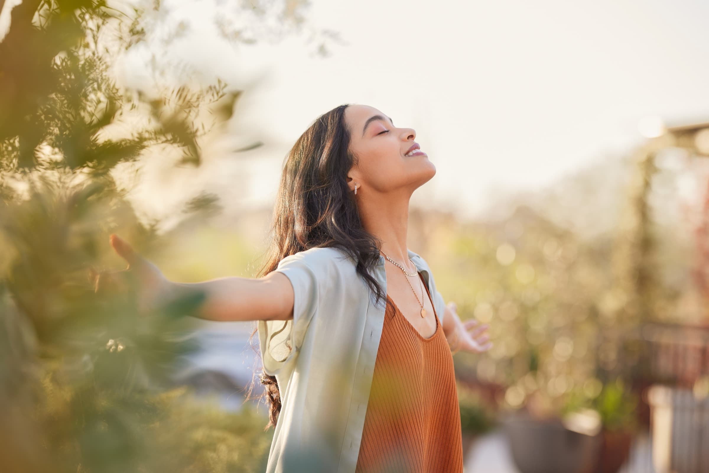 Woman standing outside in warm light with arms open